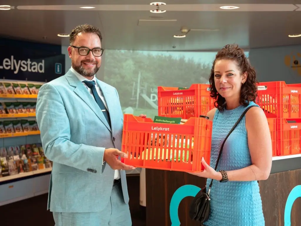 Wethouder Rhody Matthijs overhandigt de eerste Lelykrat aan een nieuwe inwoner van Lelystad.