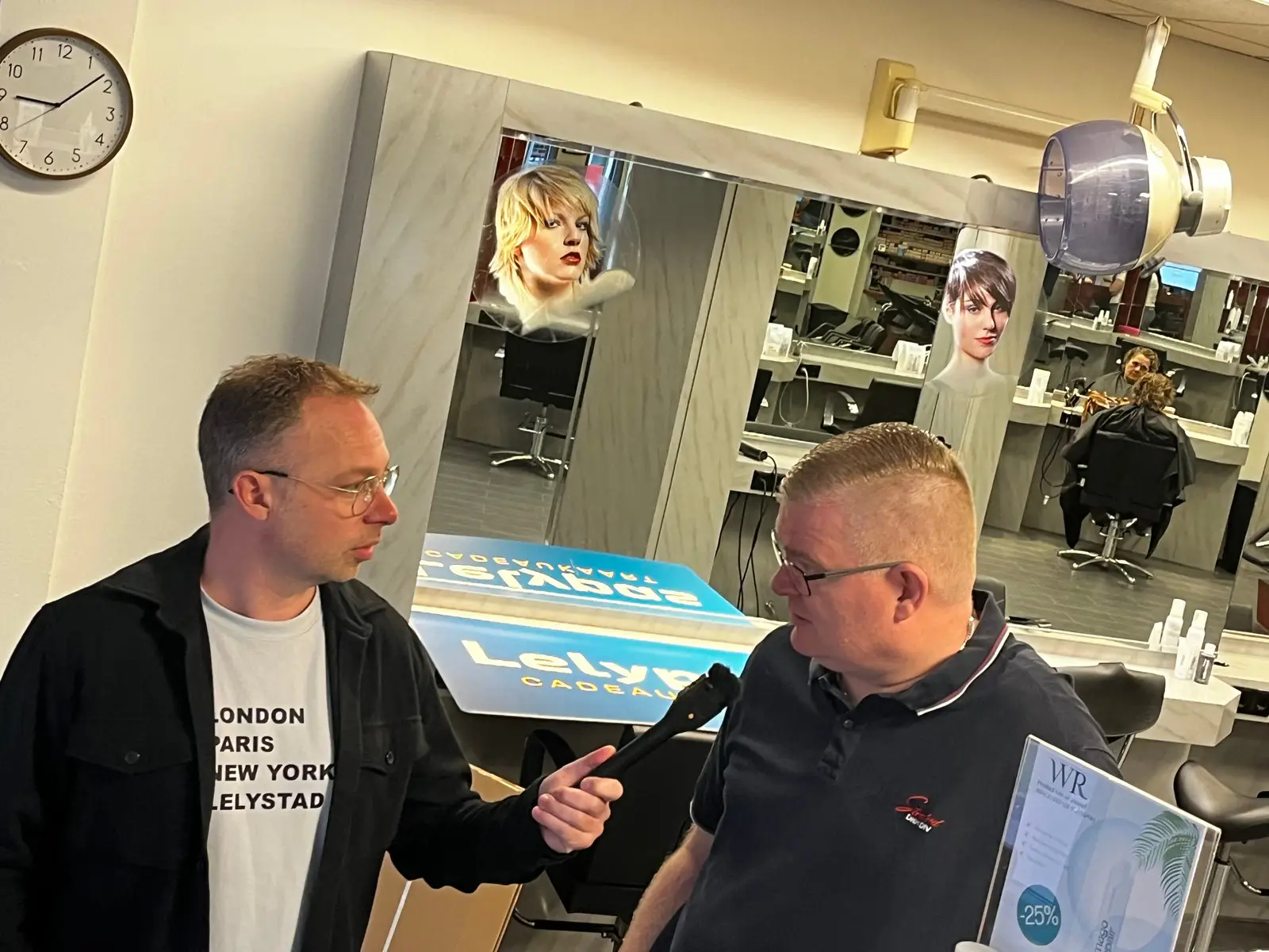 Matthijs Biesmans neemt een interview af in Walter Rombout Kapsalon.