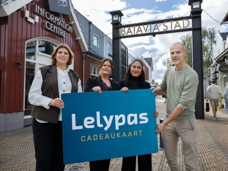 Liselore, Barbara en Meltem van Batavia Stad Information Centre en Yorick Lindeman van Stichting Lelypas met een Lelypas-bord bij de ingang van Batavia Stad.